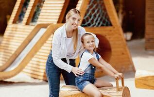 Happy Mother And Little Daughter Having Fun Posing On Playground Outside, Smiling To Camera. Family Weekend Concept photo