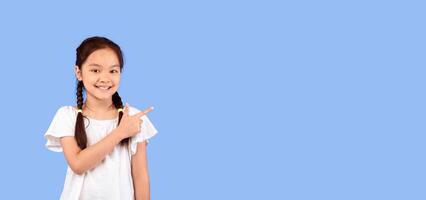 Look There. Cute Asian Little Girl Pointing Finger Aside At Empty Space Standing On Purple Background In Studio. Panorama photo