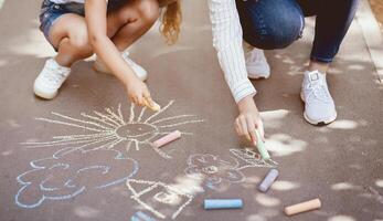 Unrecognizable Mother And Daughter Drawing Using Colorful Chalks Having Fun Outside In City Park. Cropped photo