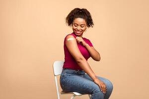 Prevention of flu. African American lady patient showing shoulder with adhesive bandage after anti flu vaccine injection on beige studio background photo