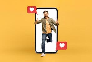 A cheerful person jumps out of a large smartphone with speech bubbles showing heart symbols. This representation highlights modern relationships and communication on social media platforms. photo