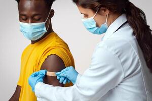 Female Nurse Applying Plaster On Black Guy's Shoulder After Injection Shot, Closeup Of Young African American Man Wearing Medical Mask Got Vaccinated Against Coronavirus, Sitting On Beige Background photo