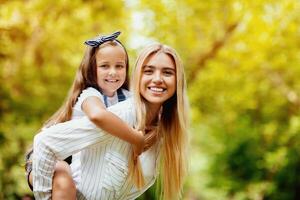 Happy Mother Carrying Daughter Piggyback Enjoying Time Together And Having Fun Outdoors Walking In Park. Free Space photo