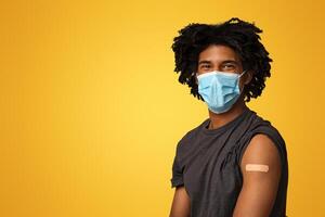 Covid-19 Vaccine. Portrait Of Black Guy In Protective Medical Mask With Adhesive Bandage On Arm Posing Over Beige Studio Background, Vaccinated African American Man Looking At Camera, Copy Space photo