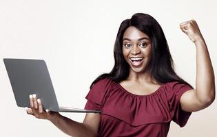 Successful young african american woman holding her brand new modern laptop, trading online, studio background, copy space. Computer, notebook, laptop, gadgets, modern technologies concept photo