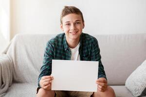Smiling teenager showing empty white board for advertising, home interior photo