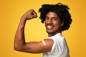 Excited African American Man Showing Arm With Plaster After Getting Covid-19 Vaccination, Happy Vaccinated Black Guy Demonstrating Biceps With Adhesive Band, Posing Over Beige Studio Background photo