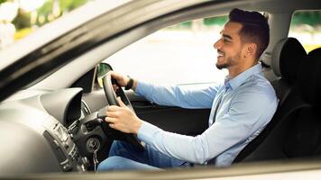 Attractive arabic guy in formal outfit sitting inside automobile, enjoying driving, going to job in the morning, side view, copy space. Auto, car, automobile, transportation concept photo