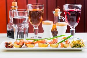 Assorted tapas and beverages served on a white plate in a cozy restaurant setting photo