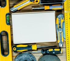 Tools and equipment arranged on a wooden surface with a blank notebook ready for notes and sketches during a DIY project photo