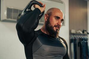 Man exercising with a kettlebell in a modern gym environment while focused on his workout routine photo