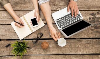 Collaboration at a wooden table with laptops, notebooks, and smartphones during a productive work session photo