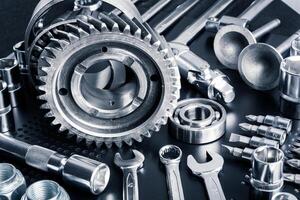 Collection of metallic tools and gears arranged neatly on a black surface in a workshop setting photo