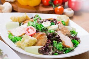 Fresh chicken salad served with vegetables and croutons in a cozy dining setting photo
