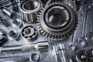 Detailed arrangement of various metallic tools and components on a workbench in a mechanic's workshop photo