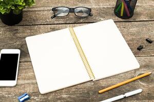 Workspace setup with stationery and a smartphone on a wooden table in a cozy indoor environment photo