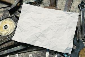 Crumpled paper placed on a workbench surrounded by various hand tools and hardware in a workshop setting photo