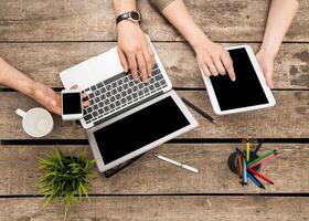 Collaborative workspace featuring multiple devices on a wooden table during a casual meeting photo