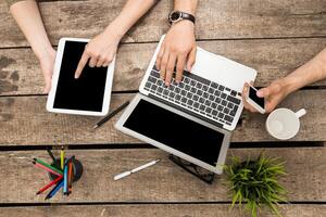 People collaborating with technology on a wooden table during a creative meeting in a bright workspace photo