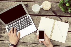 Working remotely on a wooden table with laptop, notebook, and smartphone during a productive afternoon photo