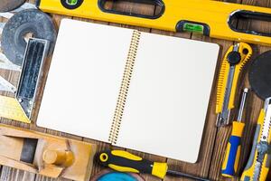 Workbench tools and blank notebook arranged on rustic wooden table for DIY projects preparation photo