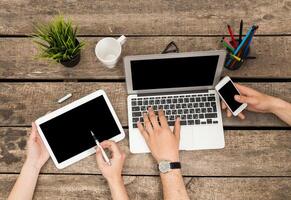 Collaboration at a rustic wooden table with digital devices during a brainstorming session photo