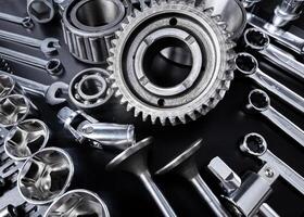 Assembly of metallic tools and parts laid out on a black surface for mechanical work photo