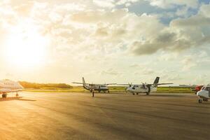 Planes parked on a runway during sunset at a small regional airport surrounded by vibrant clouds photo