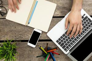 Working from home with a laptop, notepad, smartphone, and colorful pens on a wooden desk in a cozy environment photo