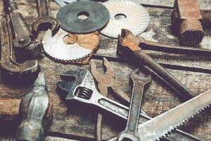 Collection of vintage hand tools and hardware components on a rustic wooden surface in a workshop setting photo