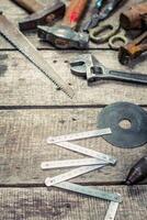 Collection of hand tools and measuring instruments arranged on a wooden workbench in a workshop photo