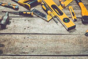Variety of hand tools arranged on a wooden surface for DIY projects in a home workshop photo