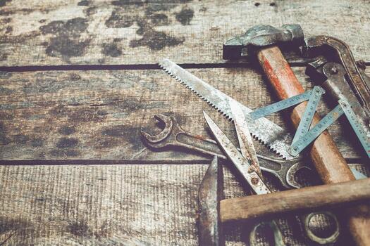 Collection of hand tools and woodworking instruments on rustic wooden surface in a workshop setting photo