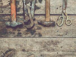 Tools arranged on a rustic wooden surface displaying various hand tools used for repair and construction work photo