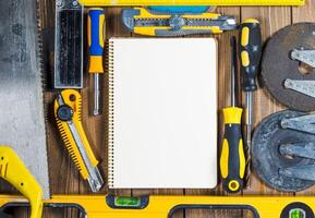 Tools and blank notepad arranged on a wooden surface in a workshop setting photo