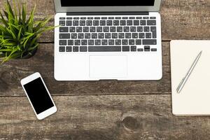 Workspace setup with laptop, smartphone, and notebook on rustic wooden table photo