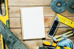 Workshop tools and a blank notebook arranged on a wooden surface for project planning photo