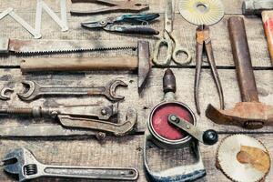 Collection of vintage hand tools arranged on a wooden workbench in a rustic workshop setting photo