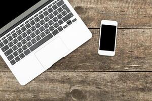 Workspace with laptop and smartphone on rustic wooden table photo