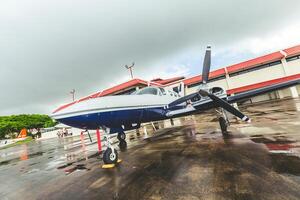 Private aircraft parked at the hangar during cloudy weather near an airport runway photo