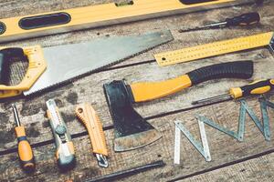 Collection of various hand tools arranged on wooden surface for carpentry and construction projects photo