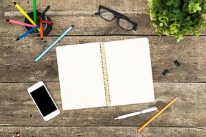 Bright workstation setup with stationery and a smartphone on a wooden table during an afternoon work session photo
