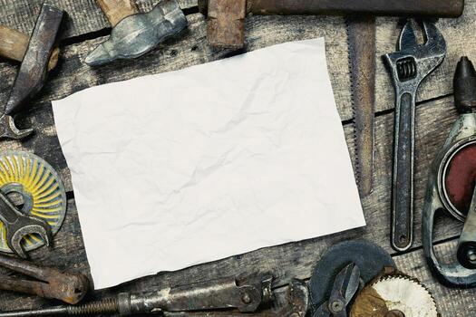 Tools arranged around a blank sheet of paper on a rustic wooden workspace for creative projects or planning sessions photo