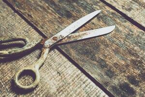 Old scissors resting on a rustic wooden table, showcasing weathered metal and vintage charm in a cozy workspace photo