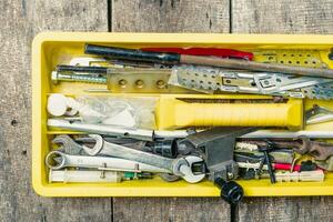 Tool box filled with various tools and implements on a rustic wooden surface in a workshop setting photo