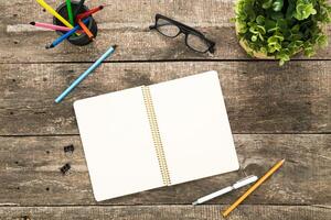 Writing tools and creative space on a wooden table with a blank notebook and stationary materials in a cozy setting photo