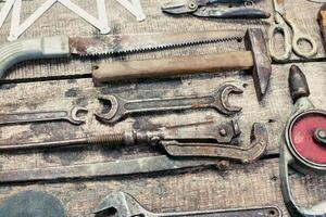 Assorted hand tools displayed on rustic wooden surface in workshop setting during daylight hours photo