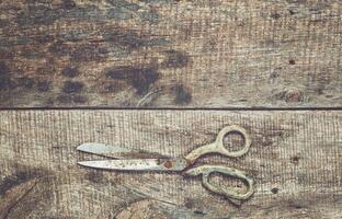 Scissors lying on rustic wooden surface with natural grain patterns, indicative of a crafting or DIY project in progress photo