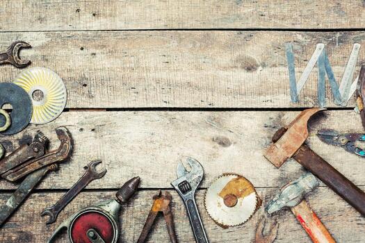 Various hand tools arranged on a rustic wooden workbench in a workshop setting showing craftsmanship and maintenance activities photo