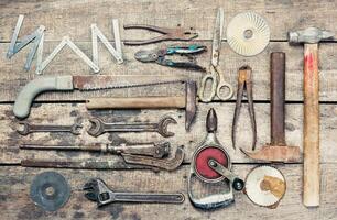 Collection of various hand tools arranged neatly on a rustic wooden surface for DIY enthusiasts and craftsmen photo